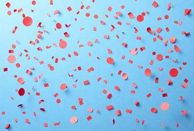 The primary subject of the image is a blue background with red and white confetti scattered across it. The confetti is in various shapes and sizes, creating a visually appealing and festive atmosphere. The setting appears to be a celebration or a special event, as the confetti is the main focus of the image. The visual style is a combination of digital art and illustration, as the confetti is skillfully placed and the overall composition is well-executed. The colors and mood of the image are vibrant and