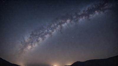 The primary subject of the image is the night sky, which is filled with stars and a beautiful view of the Milky Way. The setting is a dark, cloudy night, with the sky serving as the backdrop. The visual style of the image is a photo, capturing the stunning celestial display. The colors and mood of the image are predominantly dark and moody, with the stars and the Milky Way creating a sense of wonder and awe.