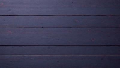 The primary subject of the image is a wooden wall with a dark blue color. The setting is a room with a wooden floor. The visual style is a close-up of the wooden wall, showcasing its texture and color. The colors and mood of the image are dark and moody, creating a sense of depth and intensity.