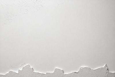 The primary subject of the image is a piece of paper with a hole in it. The paper is white, and the hole appears to be a part of the paper itself. The setting is a white wall, and the visual style is a close-up of the paper with the hole. The colors and mood of the image are predominantly white, giving it a clean and minimalist appearance.