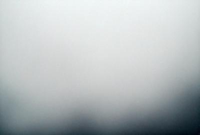 The primary subject of the image is a foggy, cloudy sky. The setting is a gray, foggy background, which creates a moody atmosphere. The visual style is a black and white photo, giving it a classic and timeless appearance. The colors and mood of the image are predominantly dark and dreary, with the fog and clouds creating a sense of mystery and solitude.