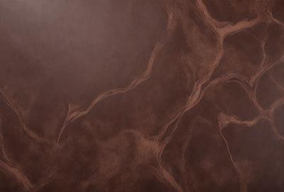 The primary subject of the image is a brown leather surface with a pattern of swirls and curves. The setting is a room with a brown wall, and the visual style is a close-up of the leather surface. The colors and mood of the image are warm and earthy, with the brown leather being the dominant color.