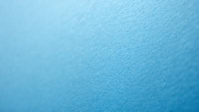 The primary subject of the image is a blue wall with a texture that resembles a blue-green paper. The setting is a room with a blue wall, and the visual style is a close-up of the wall. The colors and mood of the image are predominantly blue, creating a calm and serene atmosphere.