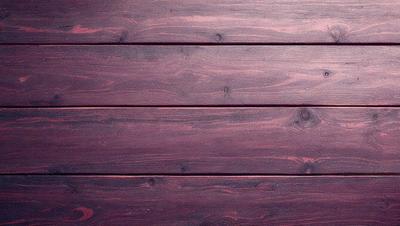 The primary subject of the image is a wooden wall with a purple tint. The setting is a room with a wooden surface, and the visual style is a close-up of the wooden wall. The colors and mood of the image are predominantly purple, creating a calm and serene atmosphere.