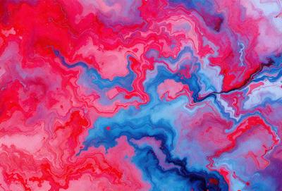 The primary subject of the image is a vibrant, colorful painting featuring a mix of red, blue, and pink hues. The painting is displayed on a wall, creating a visually striking scene. The visual style of the painting is a combination of digital art and illustration, giving it a unique and artistic appearance. The dominant colors in the painting are red, blue, and pink, creating a lively and energetic atmosphere.
