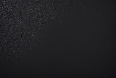 The primary subject of the image is a black background with a pattern of white dots. The setting is a dark room, and the visual style is a close-up of the pattern. The dominant colors are black and white, creating a moody atmosphere.