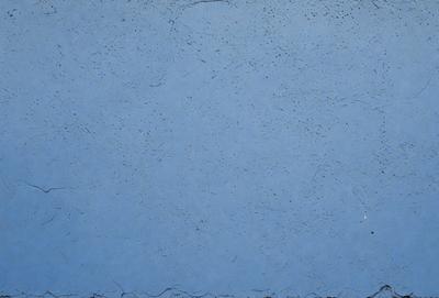 The primary subject of the image is a blue wall with a textured surface. The setting is a room with a blue wall, and the visual style is a photo. The dominant colors are blue and grey, creating a calm and serene atmosphere.