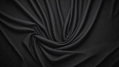 The primary subject of the image is a black fabric, which appears to be a piece of cloth or a curtain. The setting is a dark background, which emphasizes the fabric's color and texture. The visual style is a close-up of the fabric, showcasing its details and texture. The colors and mood of the image are predominantly dark, with the black fabric being the main focus.