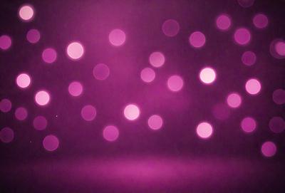 The primary subject of the image is a purple background with a pattern of pink dots. The setting is a dark room, and the visual style appears to be a digital art or illustration. The dominant colors are purple and pink, creating a calm and soothing atmosphere.