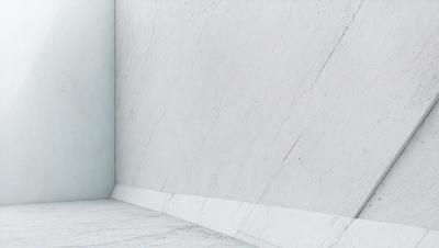 The primary subject of the image is a white marble wall. The setting is a room with a white marble floor. The visual style is a photo, and the colors and mood are predominantly white, giving the scene a clean and minimalist appearance.
