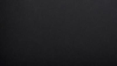 The primary subject of the image is a black background. The setting is a dark room, and the visual style is a black and white photo. The colors and mood of the image are predominantly dark and moody, with no bright colors or vibrant tones.