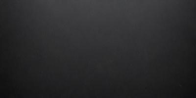 The primary subject of the image is a black leather surface. The setting is a dark room, and the visual style is a close-up of the leather surface. The colors and mood of the image are predominantly dark and moody, with the black leather surface being the main focus.