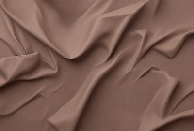 The primary subject of the image is a brown fabric, which appears to be a piece of cloth or a curtain. The setting is a room with a wall, and the visual style is a close-up of the fabric. The colors and mood of the image are warm and cozy, with the brown fabric being the dominant color.