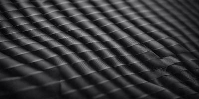 The primary subject of the image is a black fabric with a pattern of wavy lines. The setting is a black background, and the visual style appears to be a close-up of the fabric. The colors and mood of the image are predominantly black, giving it a sleek and modern appearance.