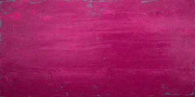 The primary subject of the image is a large, pink wall with a wood grain texture. The setting is a room with a red wall, and the visual style appears to be a photo. The dominant colors in the image are pink and red, creating a warm and vibrant atmosphere.