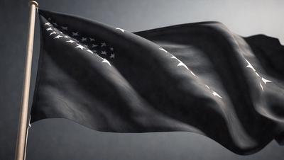 The primary subject of the image is a black flag with white stars. The setting is a gray background, which creates a contrasting effect with the flag. The visual style is a close-up of the flag, emphasizing its details. The colors and mood of the image are predominantly dark, with the white stars on the black flag providing a touch of brightness.
