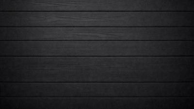 The primary subject of the image is a wooden wall. The setting is a black and white photo, which gives the image a classic and timeless appearance. The visual style is a close-up of the wooden wall, emphasizing its texture and details. The colors and mood of the image are predominantly black and white, creating a sense of depth and contrast.
