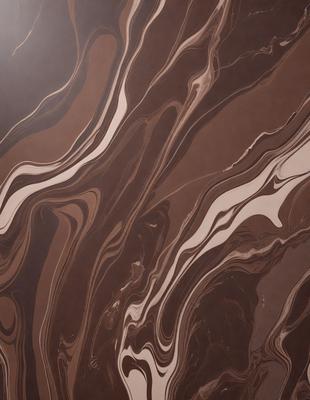 The image features a brown and white marbled pattern on a wall. The marbled pattern creates a visually appealing and textured surface. The setting appears to be a room with a brown background, which complements the marbled pattern. The visual style of the image is a combination of a photo and a digital art, as it captures the intricate details of the marbled pattern. The colors and mood of the image are warm and inviting, with the brown and white marbled pattern creating a sense of depth and soph