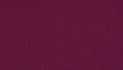The primary subject of the image is a close-up of a maroon-colored surface. The setting is a dark room, and the visual style appears to be a photo. The dominant colors in the image are maroon and black, creating a moody atmosphere.