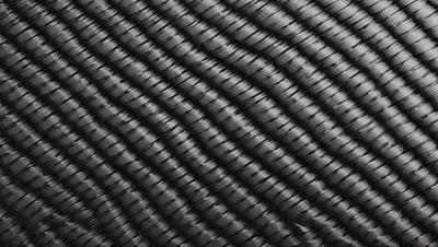 The primary subject of the image is a close-up of a black and white patterned fabric. The setting is a black background, which emphasizes the pattern. The visual style is a close-up of the fabric, showcasing its intricate design. The colors and mood of the image are predominantly black and white, giving it a classic and timeless appearance.