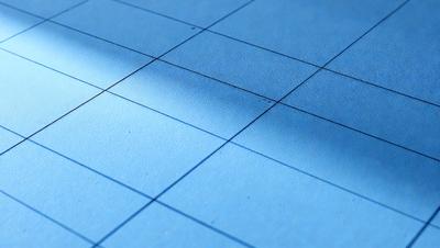 The primary subject of the image is a blue surface, which appears to be a piece of paper or a table. The setting is a room with a window, and the visual style is a close-up of the blue surface. The colors and mood of the image are predominantly blue, creating a calm and serene atmosphere.
