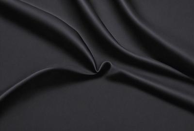The primary subject of the image is a black fabric, which is the main object, scene, or focus of the image. The setting or background is a black surface, and the visual style is a close-up of the fabric. The colors and mood of the image are predominantly black, creating a dark and moody atmosphere.