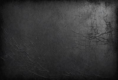 The primary subject of the image is a black wall with a texture that appears to be a combination of paint and a wallpaper. The setting is a room with a black background, which creates a dramatic and moody atmosphere. The visual style is a close-up of the wall, showcasing the intricate texture and design. The colors and mood of the image are predominantly dark, with the black wall and background creating a sense of depth and intensity.