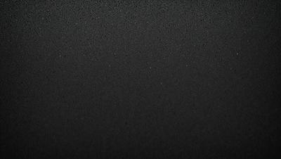 The primary subject of the image is a black background with a few white specks. The setting is a dark room, and the visual style is a black and white photo. The colors and mood of the image are predominantly dark and moody, with the white specks adding a touch of contrast.