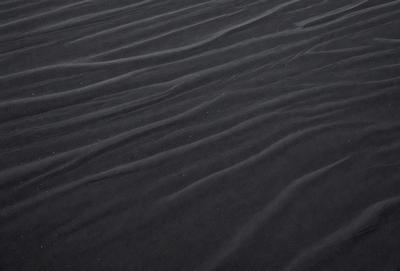 The image features a black and white sandy surface, possibly a beach or a desert. The primary subject is the sand, which is the main object, scene, or focus of the image. The setting/background is the sandy surface, and the visual style is a photo. The colors and mood of the image are predominantly black and white, giving it a classic and timeless appearance.