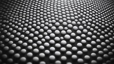 The primary subject of the image is a pattern of white circles on a black background. The circles are arranged in a visually appealing manner, creating a sense of depth and texture. The setting appears to be a black surface, possibly a wall or a piece of fabric, with the white circles standing out against it. The visual style of the image is a combination of digital art and illustration, as the circles are carefully placed and the overall composition is well-executed. The colors and mood of the image are predominantly black and