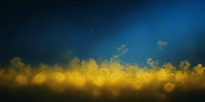 The primary subject of the image is a cloudy sky with a yellowish hue. The setting is a blue background, which contrasts with the yellow clouds. The visual style is a photo, capturing the beauty of the cloudy sky. The colors and mood of the image are warm and inviting, creating a sense of tranquility and serenity.