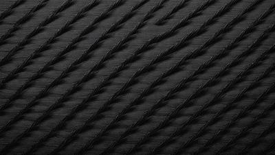 The primary subject of the image is a close-up of a black rope with a pattern of intertwining lines. The setting is a black background, which emphasizes the rope's texture and pattern. The visual style is a close-up, which highlights the intricate details of the rope. The colors and mood of the image are predominantly black, giving it a bold and striking appearance.
