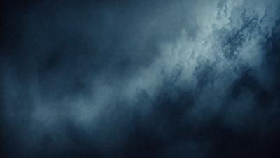 The primary subject of the image is a cloudy sky. The setting is a dark, cloudy night with a blue hue. The visual style is a black and white photo, giving it a classic and timeless appearance. The colors and mood convey a sense of mystery and tranquility, as the viewer is left to imagine the beauty of the night sky.