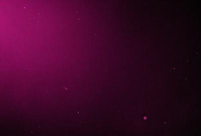 The primary subject of the image is a purple background with a few white stars scattered throughout the scene. The setting appears to be a dark, starry sky, and the visual style is a combination of a photo and digital art. The colors and mood of the image are predominantly purple and dark, creating a sense of mystery and depth.