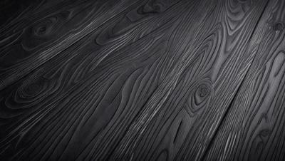 The primary subject of the image is a wooden floor with a unique and intricate pattern. The setting is a room with a black background, which emphasizes the wooden floor's design. The visual style is a close-up of the wooden floor, showcasing its details. The colors and mood of the image are dark and moody, with the wooden floor being the main focus.