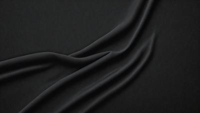 The primary subject of the image is a black cloth, which is the main object, scene, or focus of the image. The setting or background is a dark surface, and the visual style is a close-up of the cloth. The colors and mood of the image are predominantly dark, with the black cloth being the dominant color.