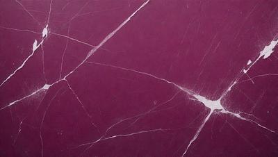 The primary subject of the image is a marble surface with a purple hue. The setting is a room with a purple wall, and the visual style is a close-up of the marble surface. The colors and mood of the image are predominantly purple, creating a calm and sophisticated atmosphere.