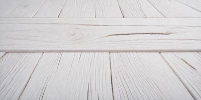 The primary subject of the image is a wooden floor with a white surface. The setting is indoors, possibly in a room or a house. The visual style is a photo, capturing the wooden floor with its unique texture and pattern. The colors and mood of the image are predominantly white, giving it a clean and minimalist appearance.