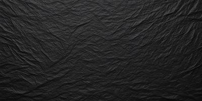 The primary subject of the image is a black cloth with a pattern of wrinkles and folds. The setting is a dark background, which contrasts with the cloth. The visual style is a close-up of the cloth, showcasing its texture and pattern. The colors and mood of the image are predominantly dark, with the black cloth being the main focus.