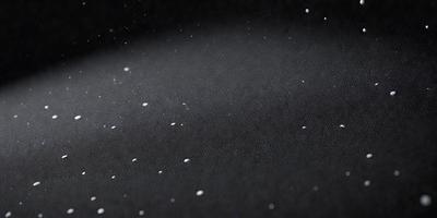 The primary subject of the image is a black background with white specks or dots scattered across it. The setting appears to be a dark room, and the visual style is a close-up of the black background with the white specks. The colors and mood of the image are predominantly dark and moody, with the white specks adding a touch of contrast and interest to the overall composition.