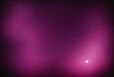 The primary subject of the image is a pink background with a purple hue. The setting is a dark, cloudy sky, creating a moody atmosphere. The visual style is a combination of a photo and digital art, as the background appears to be a blend of the two. The colors and mood of the image are predominantly pink and purple, giving it a warm and somewhat mysterious feel.