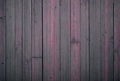 The primary subject of the image is a wooden floor with a purple stain. The setting is a room with a wooden floor, and the visual style is a close-up of the wooden floor. The colors and mood of the image are predominantly purple, giving it a unique and artistic appearance.