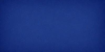 The primary subject of the image is a large, dark blue surface. The setting is a vast, empty space with no visible objects or backdrop. The visual style is a simple, unadorned representation of the blue surface. The colors and mood of the image are predominantly dark and moody, with the blue surface being the main focus.