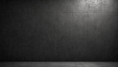 The primary subject of the image is a large, grey concrete wall. The setting is a room with a concrete floor, and the visual style is a black and white photo. The dominant colors are grey and black, creating a stark and minimalist atmosphere.