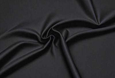 The primary subject of the image is a black fabric, which is the main object, scene, or focus of the image. The setting or background is a black surface, and the visual style is a photo. The colors and mood of the image are predominantly black, creating a dark and moody atmosphere.