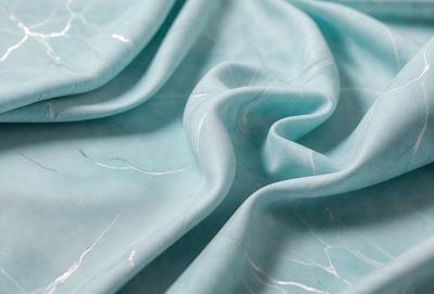 The primary subject of the image is a blue fabric, possibly a piece of cloth or a curtain. The setting is a blue background, which complements the blue fabric. The visual style appears to be a close-up of the fabric, showcasing its texture and details. The colors and mood of the image are predominantly blue, creating a calm and serene atmosphere.