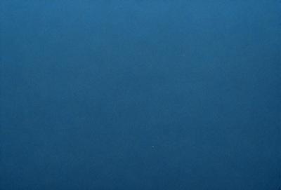 The primary subject of the image is a large, dark blue surface. The setting is a vast, open space with no visible objects or people. The visual style is a close-up of the blue surface, which gives a sense of depth and dimension. The colors and mood of the image are predominantly dark and moody, with the blue surface being the main focus.