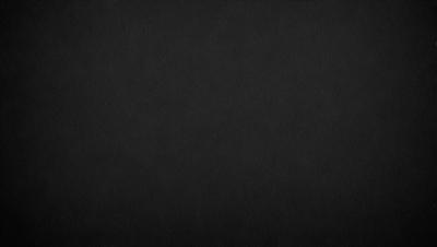 The image is a black and white photo of a dark background. The primary subject is a large, empty space with no visible objects or details. The setting is a black background, which creates a stark contrast with the subject. The visual style is a black and white photo, giving the image a classic and timeless appearance. The colors and mood are predominantly dark and moody, with the black background emphasizing the emptiness of the space.