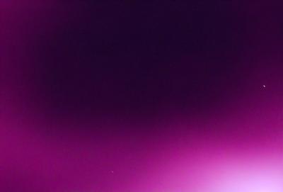 The primary subject of the image is a purple background. The setting is a dark, pinkish sky, which creates a moody atmosphere. The visual style is a close-up of the purple background, emphasizing its vibrant color. The colors and mood of the image are predominantly purple, giving it a unique and striking appearance.