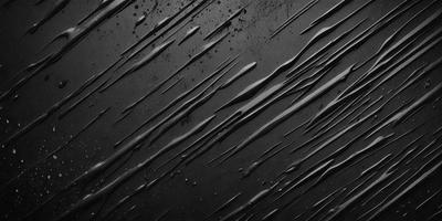 The primary subject of the image is a close-up of a black surface with a pattern of dripping water. The setting appears to be a dark room, and the visual style is a black and white photo. The colors and mood of the image are predominantly dark and moody, with the dripping water creating a sense of depth and intrigue.